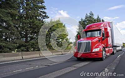 Bright modern long haul big rig semi truck with semi trailer moving on the green road Stock Photo