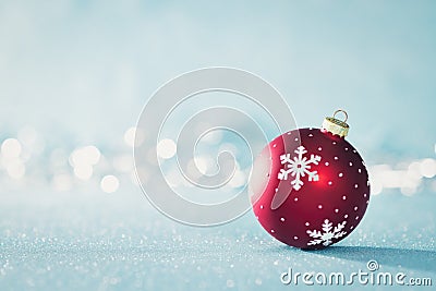 Bright Red Christmas Bauble in Winter Wonderland. Blue Christmas background with defocused christmas lights. Stock Photo