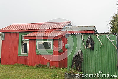 Bright red and green holiday home or batch in remote New Zealand coastal town Editorial Stock Photo