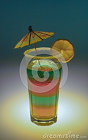 bright rich exotic cocktail in a tall glass with an umbrella and a piece of fruit on a colored background Stock Photo