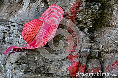 A bright and rich pink hat with a stripe pattern and a matching satin ribbon bow hangs Stock Photo