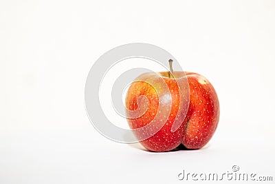 Bright ripe red apple of an unusual shape in the shape of an ass in the light of the sun Stock Photo