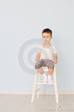 Bright room. Boy in white shirt sitting in a high chair Stock Photo