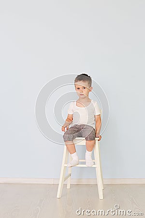 Bright room. Boy in white shirt sitting in a high chair Stock Photo