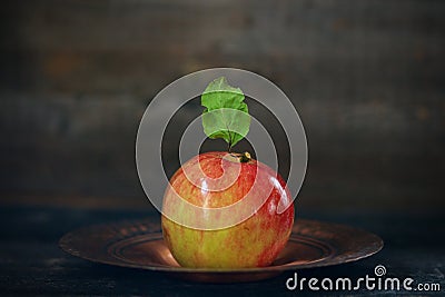 Bright and shiney crab apple with attached leaf on a plate Stock Photo