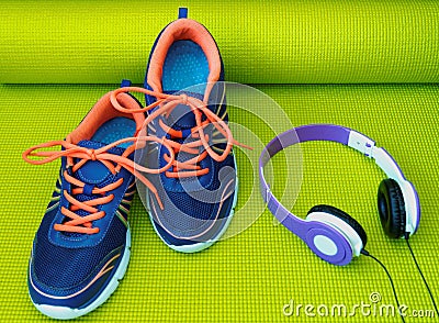 Bright Shoes and Headphones on Rolled Yoga Mat Stock Photo