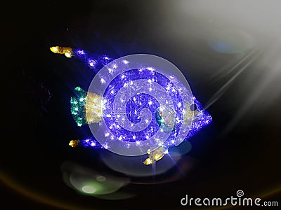 Bright sparkling blue fish in dark ocean under above sun light Stock Photo