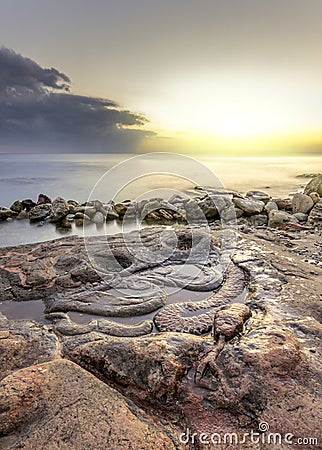 Bright sun at sunset, illuminating the stone snake Stock Photo