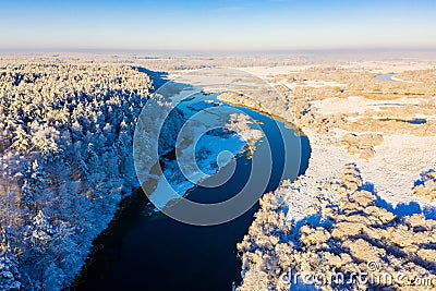 Bright sunny day starts in winter valley, aerial landscape. River curves near thick snowy forest Stock Photo