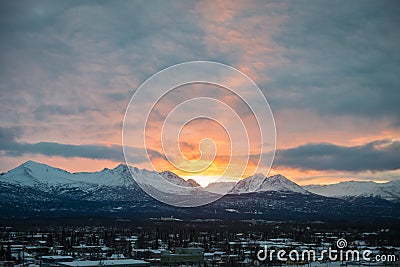 Bright sunrise behind mountains on a cloudy winter day Stock Photo