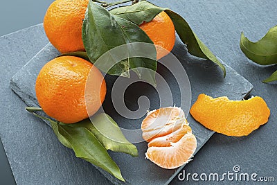 Bright tangerines with leaves on the slate plate background Stock Photo
