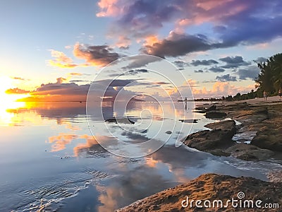 Bright tropial sunset reflected in ocean water Stock Photo