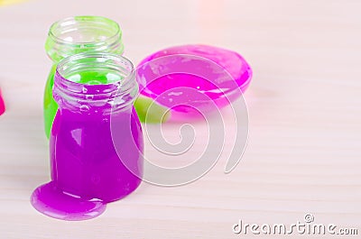 Bright violet slime spilling of from the bottle. Elastic glue with glitter worldwide popular kids toy Stock Photo