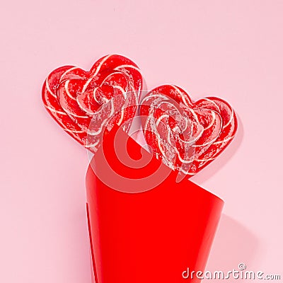 Bright wedding background - couple sweet red lollipops hearts as bouquet on pastel pink, square. Stock Photo