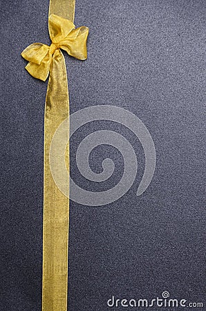 Bright yellow bow and ribbon made of organza on the black background.Vertical shot, empty space for text Stock Photo