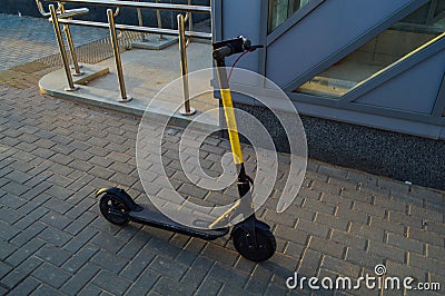 A bright yellow electric scooter stands in the city center for people to ride. rent transport for movement. charged from the mains Stock Photo