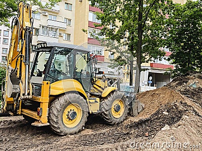 Bright, yellow excavator digs a hole in the sand. construction machinery. reliable road and pit construction vehicle drives Stock Photo