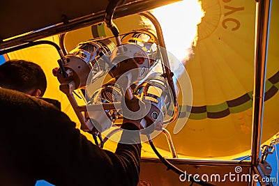 Bright yellow hot air balloon flying with gas fire flame heat equipment by pilot over Cappadocia, low angle view from inside Editorial Stock Photo