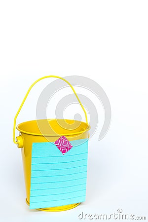 Bright yellow metal pail with aqua colored lined paper taped to front with pink washi tape on solid white background Stock Photo