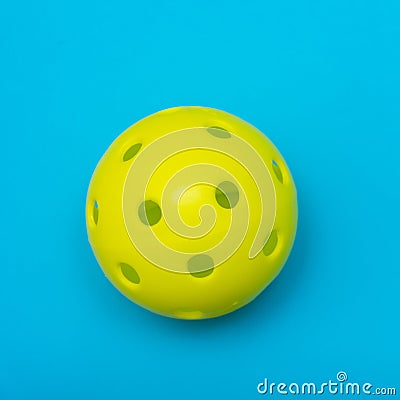 Bright yellow pickleball or whiffle ball on a solid aqua blue flat lay background symbolizing sports and activity with copy space Stock Photo