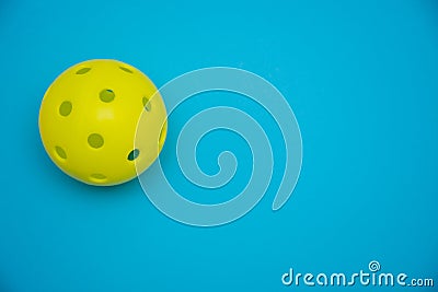 Bright yellow pickleball or whiffle ball on a solid bright blue flat lay background symbolizing sports and activity with copy Stock Photo