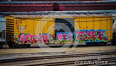 Bright yellow railroad car tagged with graffiti Editorial Stock Photo