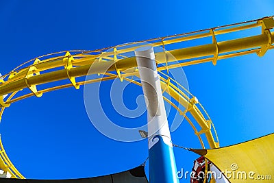 A bright yellow rollercoaster track with a gorgeous blue sky at Santa Monica Pier in Santa Monica Editorial Stock Photo