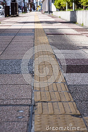 Bright yellow tactile footpath for people who have visually impaired on the walkway. Stock Photo