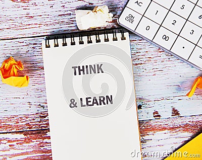 Brightly arranged on a wooden surface, a notebook displays THINK and LEARN, accompanied by a calculator and crumpled Stock Photo