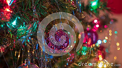 Brightly colored, cheery Christmas tree ornaments hung up with lights and tinsel Stock Photo