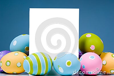 Brightly colored Easter Eggs surrounding white, blank notecard Stock Photo
