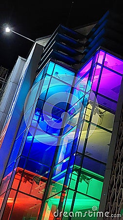 Brightly colored illuminated glass facade of house at night Stock Photo