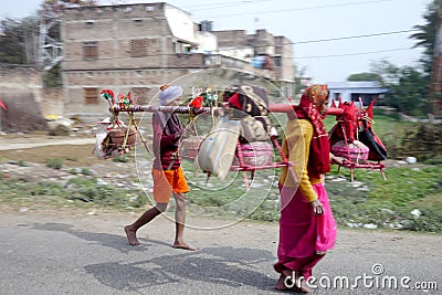 Brightly dressed religious pilgrims walk alongside the road in rural India. Editorial Stock Photo