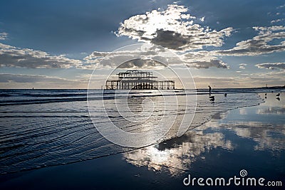 Brighton west Pier at sunset with a solitary man walking into the sea Stock Photo