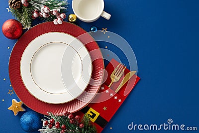 Top view arrangement, complete with Santa's holder for golden flatware, cup, balls, confetti and festive adornments on blue Stock Photo