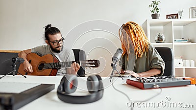 Bring music to life. Man playing guitar and woman smiling, playing rhythm with djembe drum. Couple of musicians Stock Photo