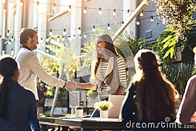 Bringing fresh business expertise to the team. colleagues shaking hands during a meeting at an outdoor cafe. Stock Photo