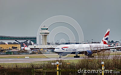 A British Airways plane taxis after landing at London Gatwick Airport, with the air traffic control tower in the background Editorial Stock Photo