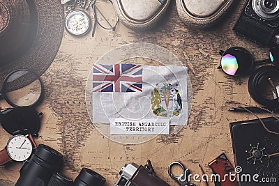 British Antarctic Territory Flag Between Traveler`s Accessories on Old Vintage Map. Overhead Shot Stock Photo