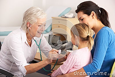 British GP examining young child with mother Stock Photo