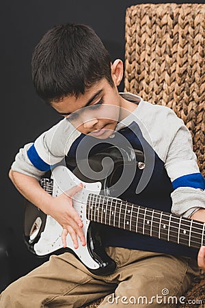 8 year old British Indian boy practices the electric guitar at home. Stock Photo