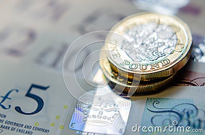 British money. Macro photo of One Pound coins and the British pound banknotes of different denomination Editorial Stock Photo