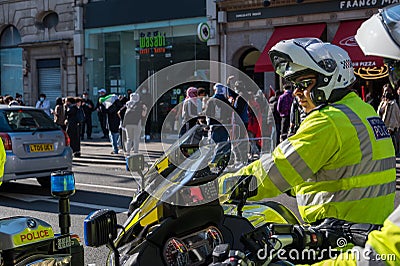 British police motorcyclist with Freedom for Palestine protest rally on a London street in the background Editorial Stock Photo