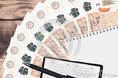 10 British pounds bills fan and notepad with contact book and black pen. Concept of financial planning and business strategy Editorial Stock Photo