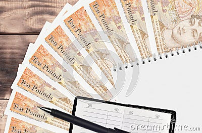 10 British pounds bills fan and notepad with contact book and black pen. Concept of financial planning and business strategy Editorial Stock Photo