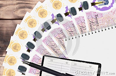 20 British pounds bills fan and notepad with contact book and black pen. Concept of financial planning and business strategy Editorial Stock Photo