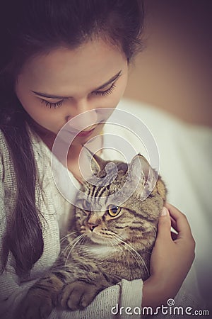 British shorthair cat with casual dressed woman who is holding and petting cute cat resting at home Stock Photo