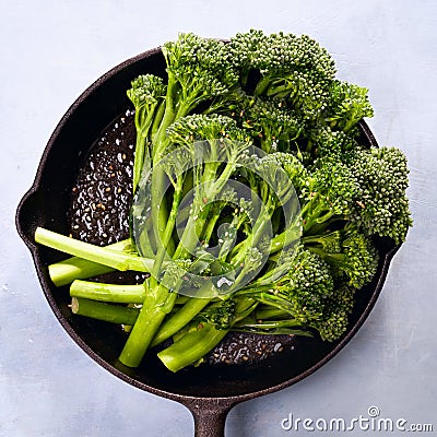 Broccolini fresh organic broccoli florets green vegetable baby broccoli, olive oil, sesame seeds in cast iron pan, vegan raw Stock Photo