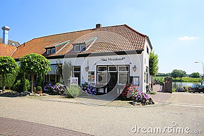 View on old rural tourist hotel at river maas near ferry pier in small dutch village in summer Editorial Stock Photo