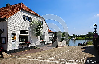 View on old rural tourist hotel at river maas near ferry pier in small dutch village in summer Editorial Stock Photo